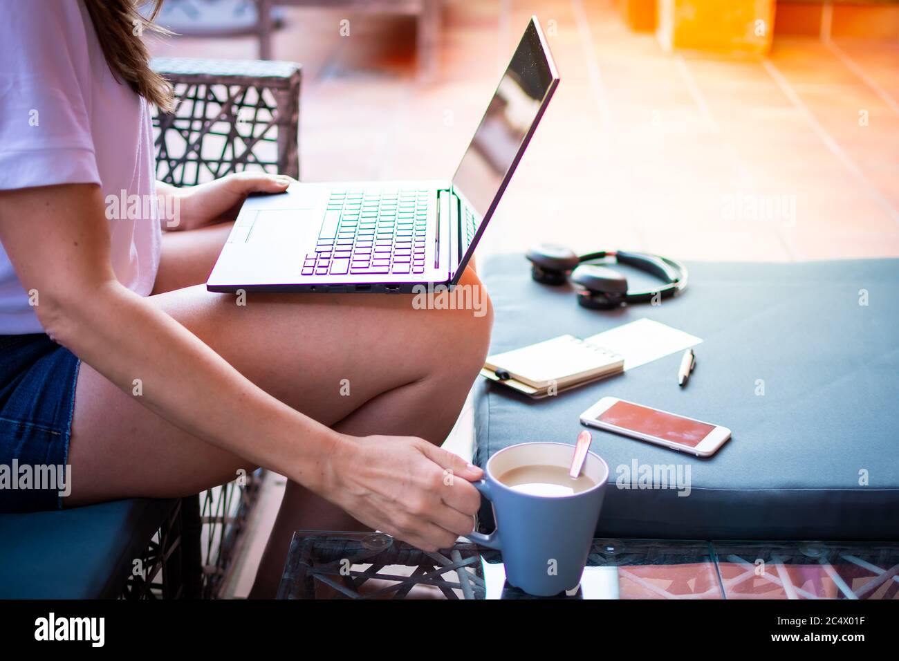 Bella ragazza seduta con un laptop su una chaise longue, una donna che lavora in vacanza, ricerca di lavoro Foto Stock