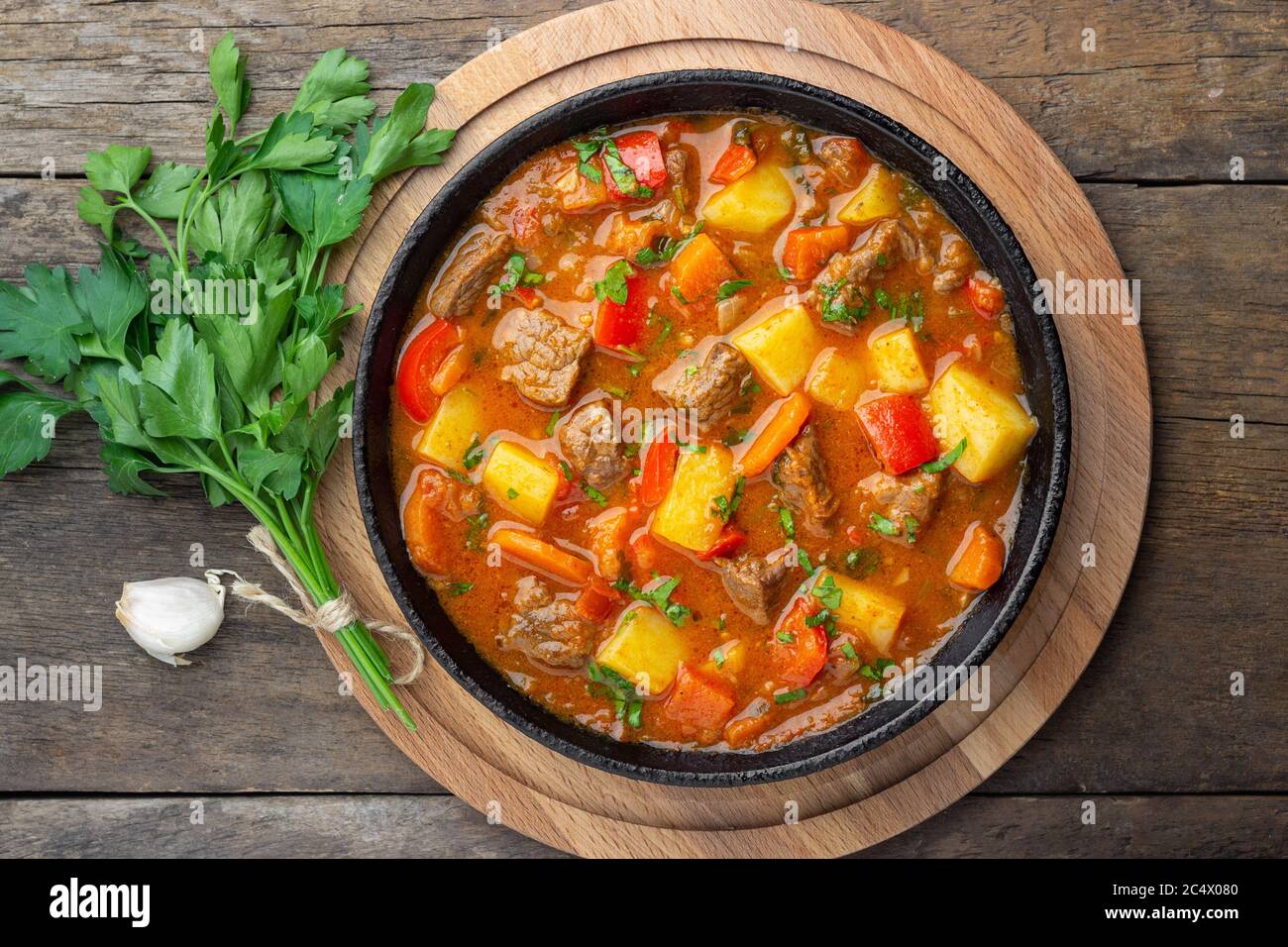 Goulash, stufato di manzo o zuppa di bogrash con carne, verdure e spezie in padella di ghisa su tavola di legno. Cucina ungherese. Stile rustico. Vista dall'alto. Foto Stock