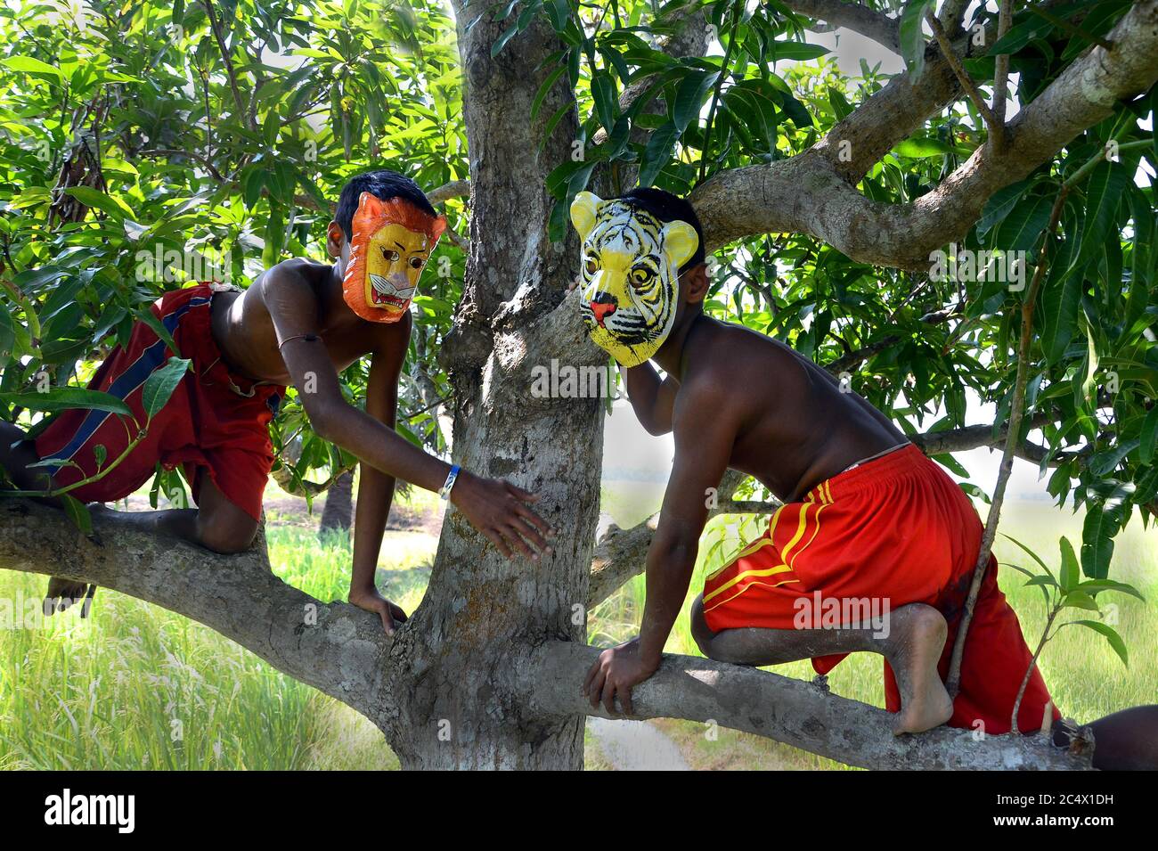 Il remoto villaggio di bambini piccoli stanno giocando con la maschera tigre per il messaggio alla gente del villaggio per salvare la tigre a Sundarban, India Bengala Occidentale. Foto Stock