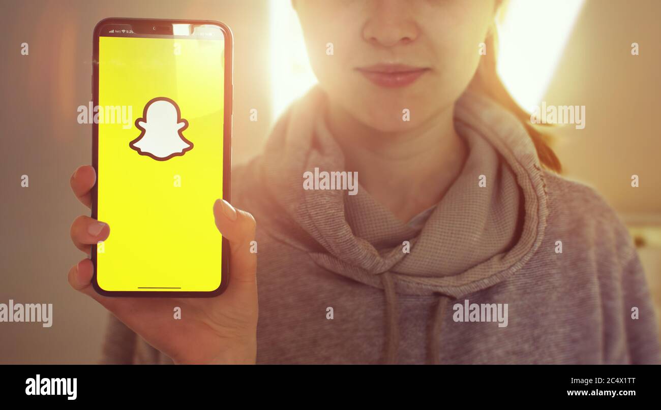 KIEV, UCRAINA-GENNAIO, 2020: Snapchat sullo schermo del cellulare. Giovane ragazza che mostra lo schermo del telefono intelligente con Snapchat mentre si guarda la fotocamera. Attenzione allo smartphone. Foto Stock