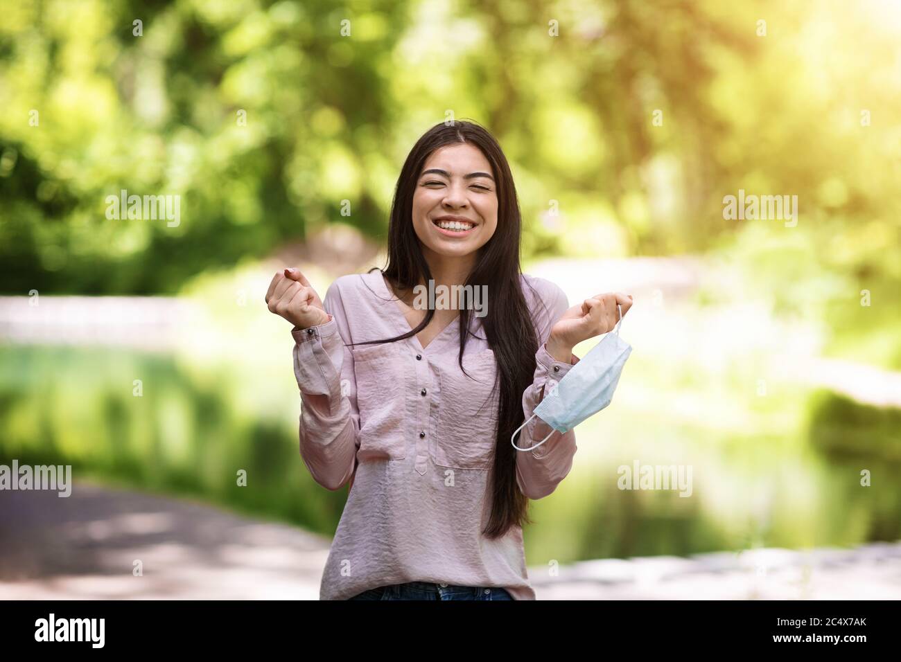 La quarantena è finita. Ragazza asiatica felice rimozione maschera all'aperto e celebrare la vittoria Foto Stock