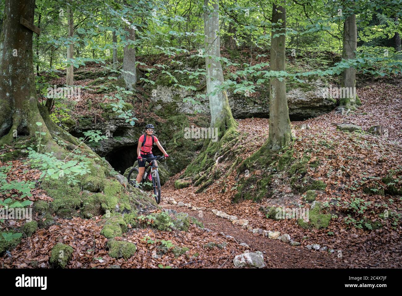 Donna anziana in fase di svolgimento sulla sua mountain bike elettrica su un sentiero roccioso nella Svizzera Franconia, Baviera, Germania Foto Stock