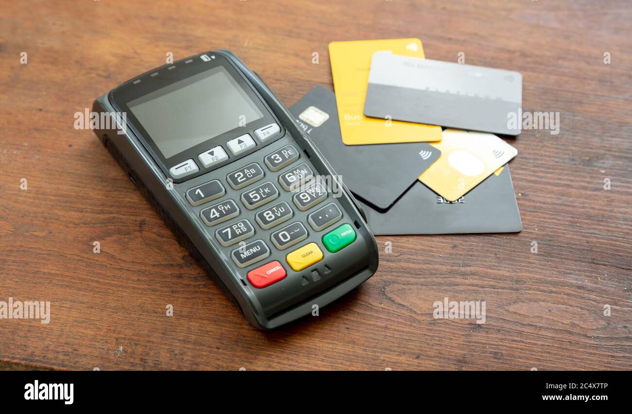 Terminale POS e carte di credito su sfondo ligneo, terminale registratore di cassa per pagamenti senza contatto. Apparecchiature bancarie, consumismo, shopping c Foto Stock