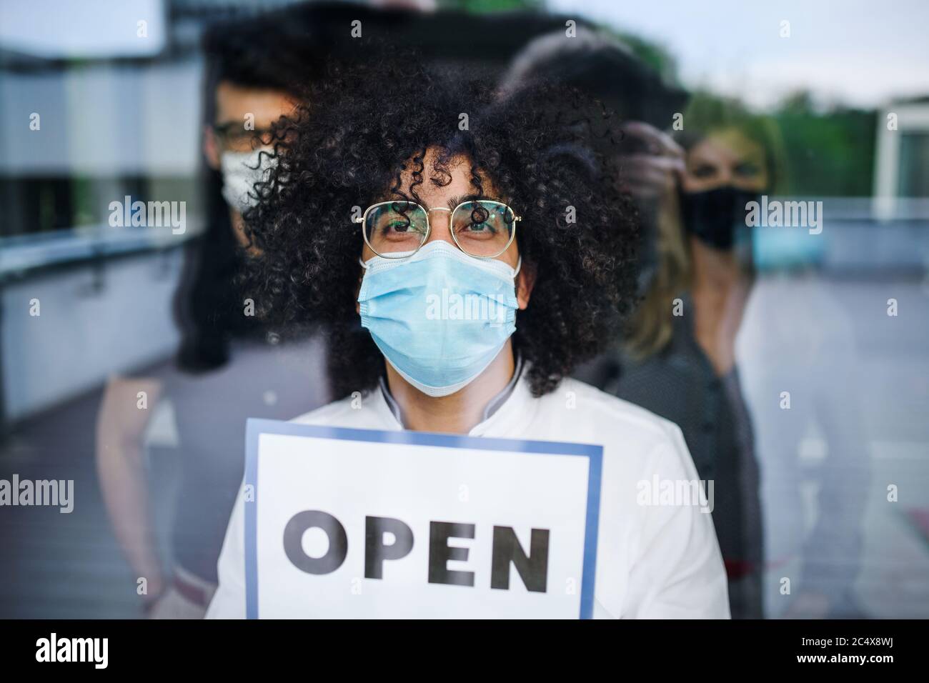Ritratto dell'uomo con maschera facciale che tiene aperto segno, quarantena e concetto di blocco. Foto Stock