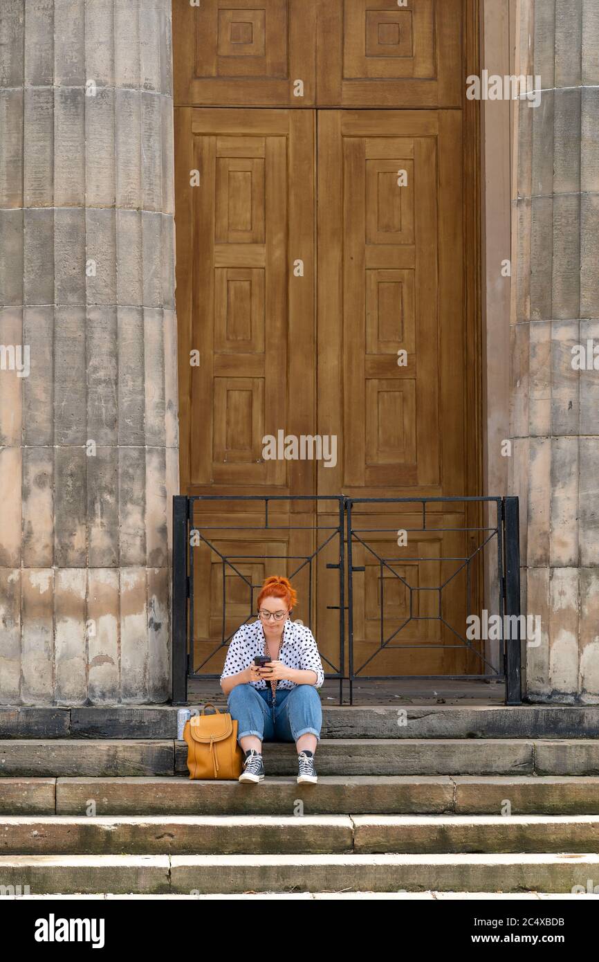 Elgin High Street, Moray, Regno Unito. 29 Giugno 2020. REGNO UNITO. Questa è una signora seduta sui gradini della chiesa di San Giles su Elgin High Street con i negozi che sono ora in apertura. Credit: JASPERIMAGE/Alamy Live News Foto Stock