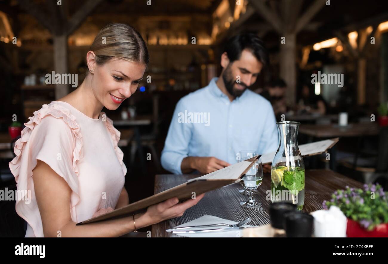 Una coppia felice, seduta all'interno del ristorante, guardando il menu. Foto Stock