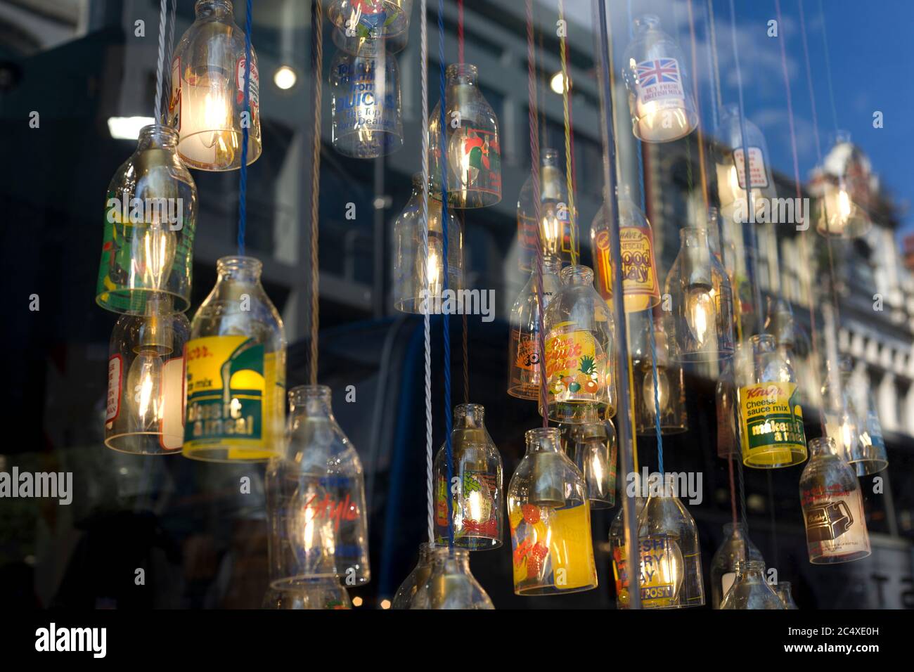 Bottiglie di marca come dispositivi di illuminazione in una vetrina negozi. Finestre creative, display creativi Foto Stock