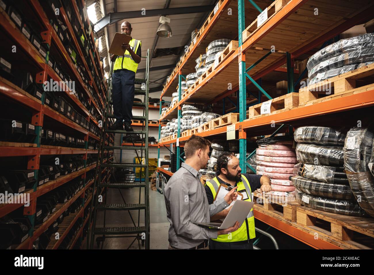 Tre operai di fabbrica maschili che controllano le scorte in fabbrica Foto Stock