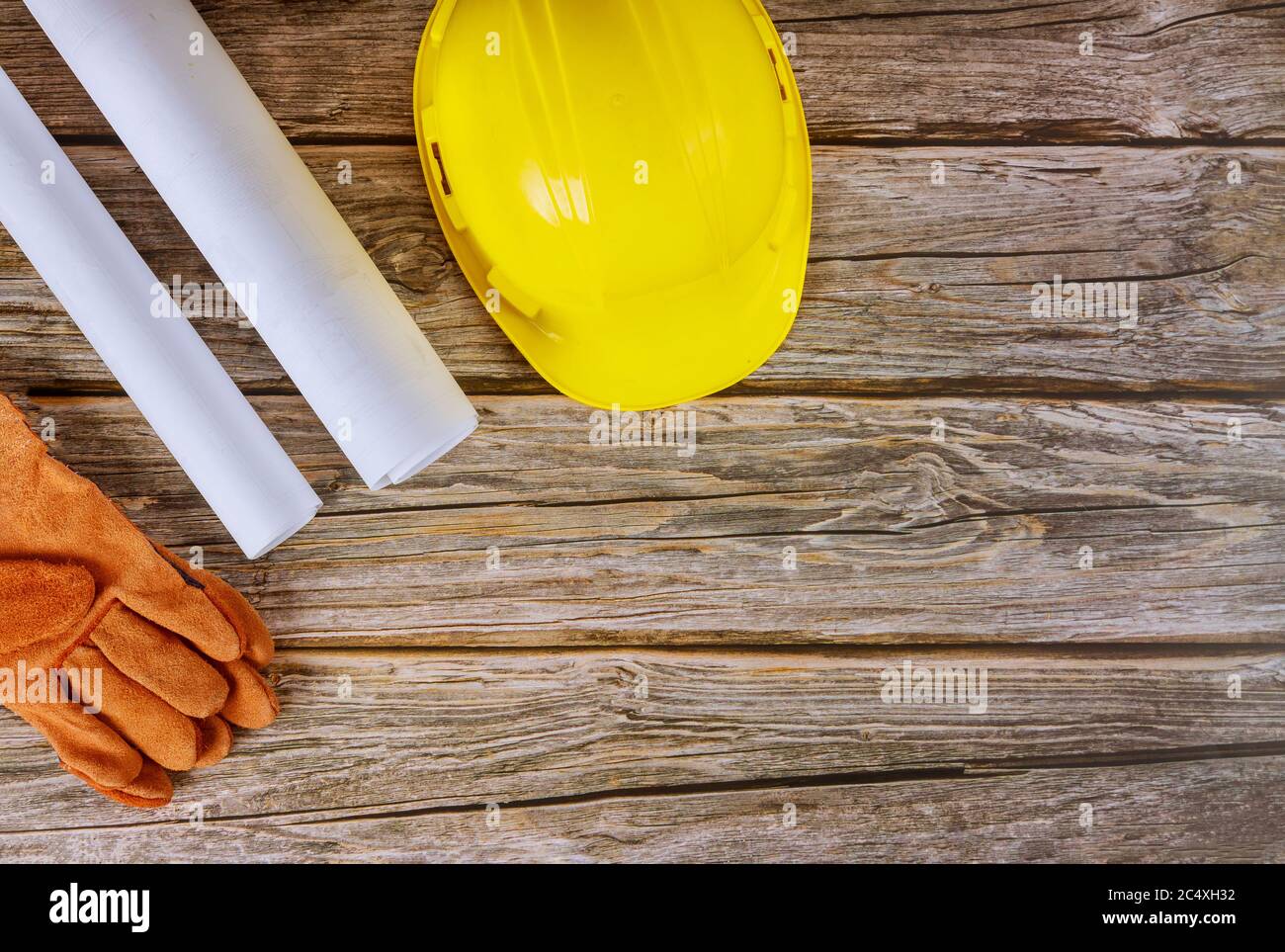 Costruttore di architetti progetta lavorando su progetti di costruzione di uffici di ingegneria piani di sicurezza guanti su elmetto di sicurezza giallo Foto Stock