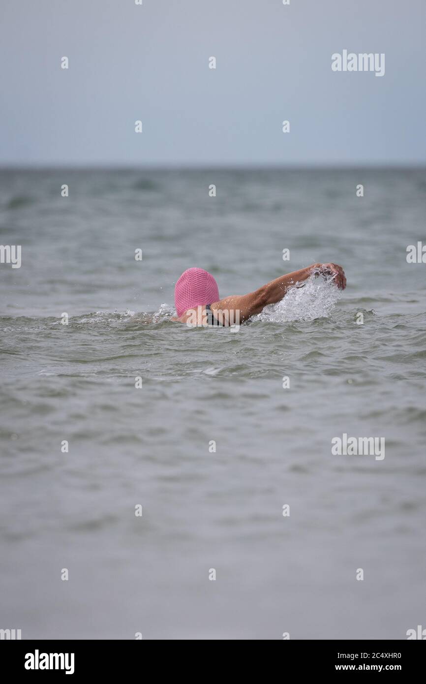 11 giugno 2020, Schleswig-Holstein, Westerland/Sylt: Una donna con una cuffia rosa nuota nel Mare del Nord sulla spiaggia di Westerland, in Sylt. Foto: Christian Charisius/dpa Foto Stock