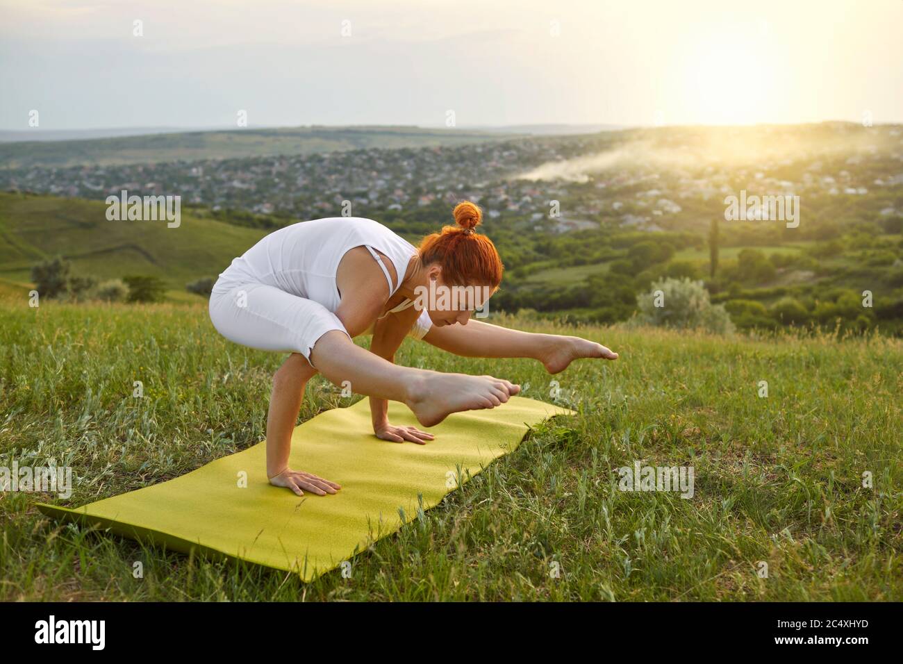 Meditazione yoga in natura. Giovane ragazza flessibile che fa yoga sulla cima della montagna all'alba. Foto Stock