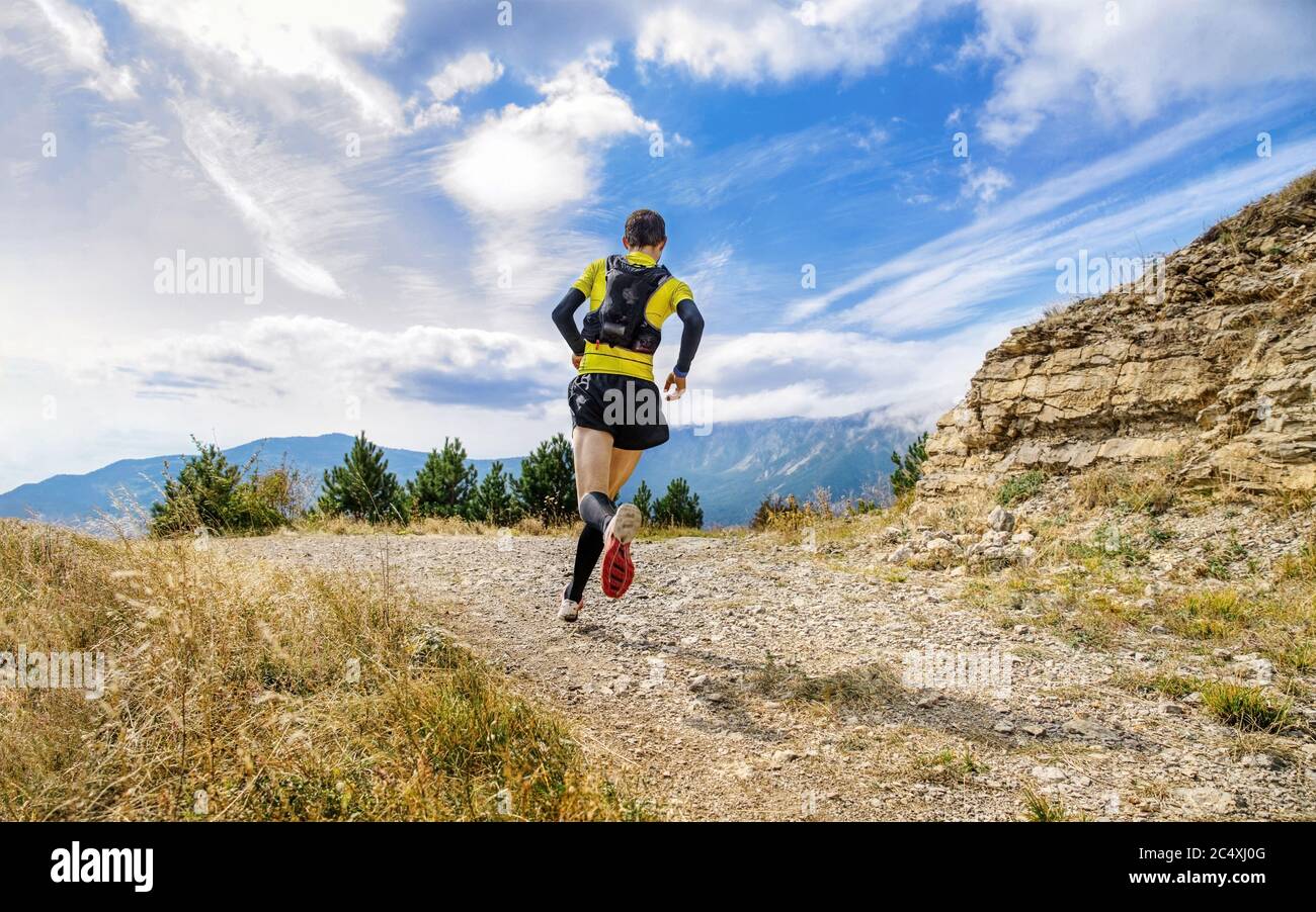 atleta corridore correre montagna sentiero maratona in fondo cielo blu Foto Stock