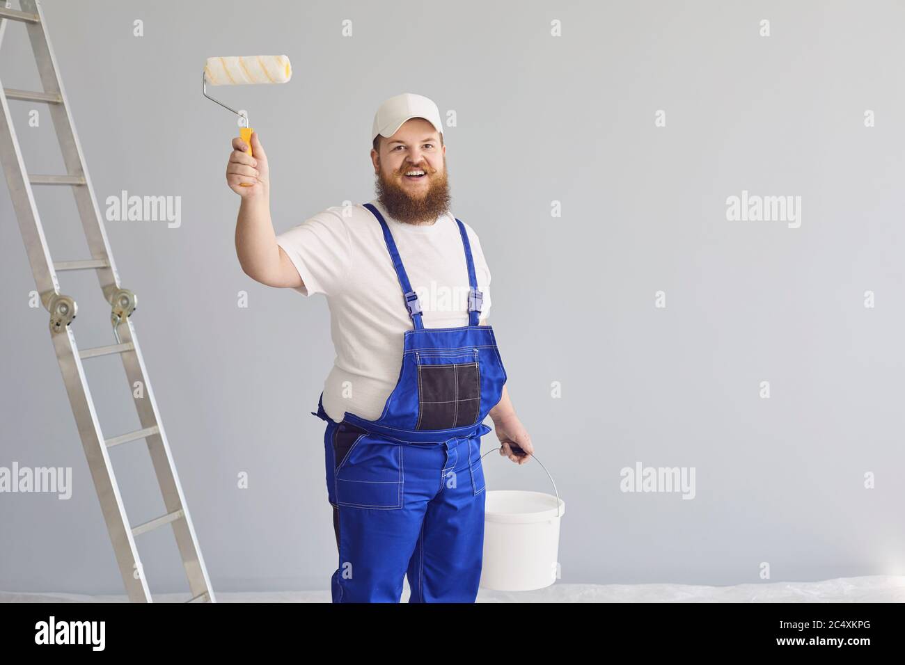 Pittura di pittore. Divertente pittore maschile con un pattinatore a rulli in piedi dipinge sullo sfondo. Foto Stock