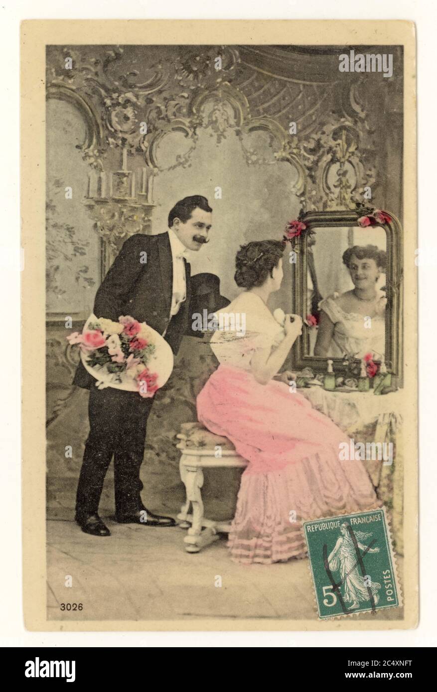 Primo 1900's francese sentimentale tinta saluti scheda - due giovani amanti, uomo con bouquet, donna seduta ad un tavolo da toletta, Francia, circa 1911 Foto Stock