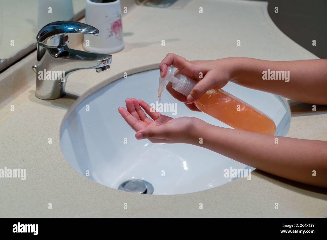 Un bambino che pompava sapone da un dispenser di bottiglie sul palmo per proteggerlo da germi, virus e malattie per rimanere pulito e igienico. Foto Stock