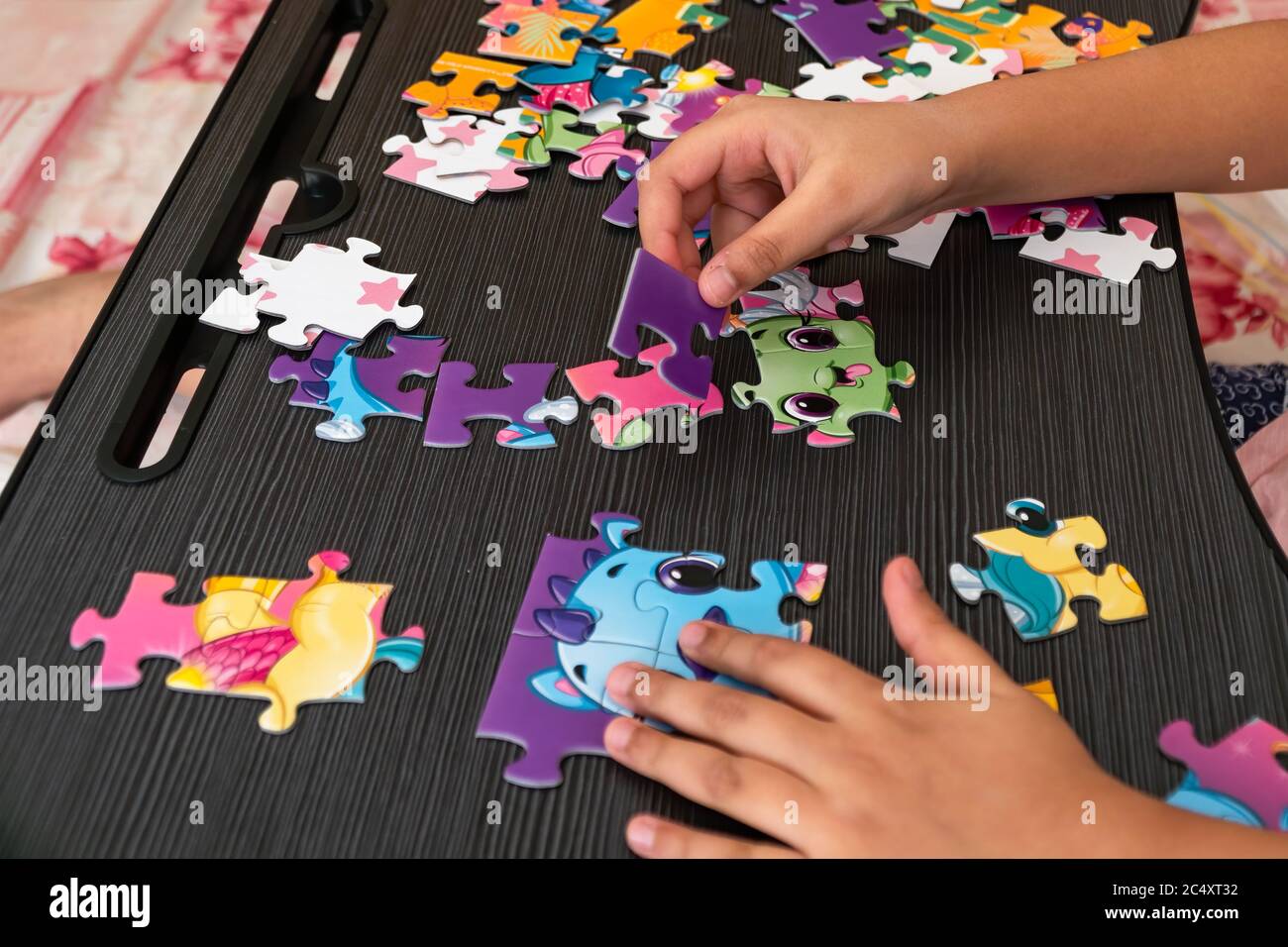 Un bambino gioca un gioco, cercando di risolvere un puzzle Jigsaw. Foto Stock