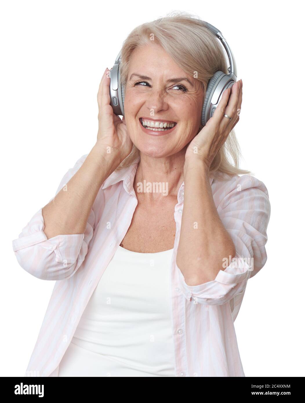 Bella donna bionda senior sta ascoltando musica in cuffie wireless isolate su sfondo bianco Foto Stock