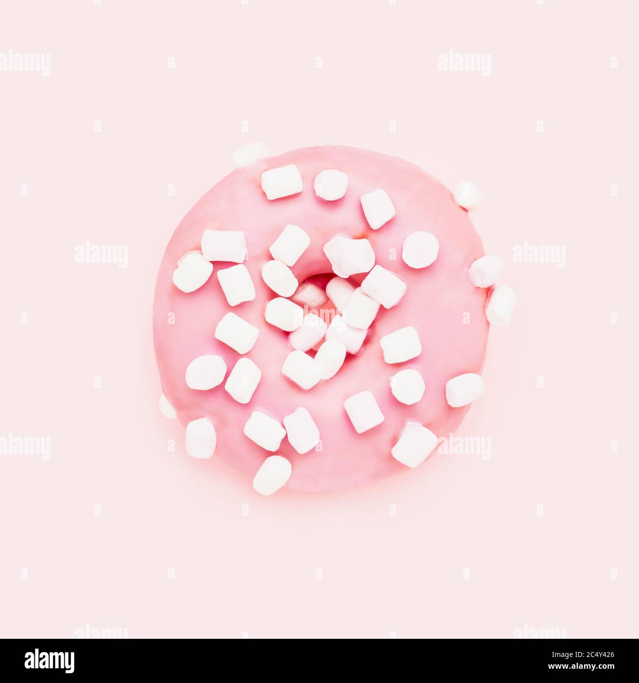 Ciambella rosa con spruzzi bianchi su sfondo rosa. Vista dall'alto, spazio di copia per il testo Foto Stock