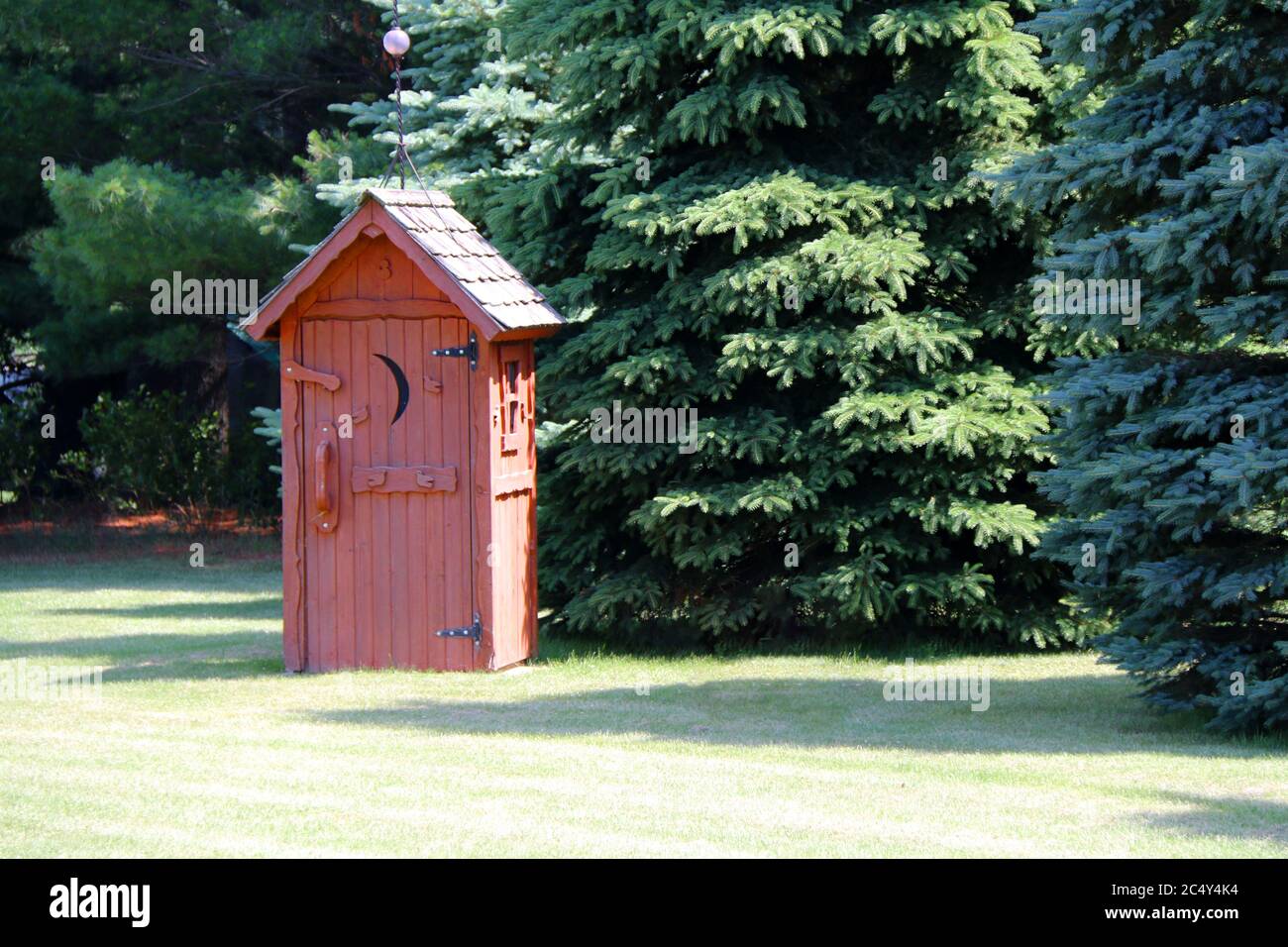 un edificio rurale rosso outhouse privato wc in una soleggiata foresta glade Foto Stock