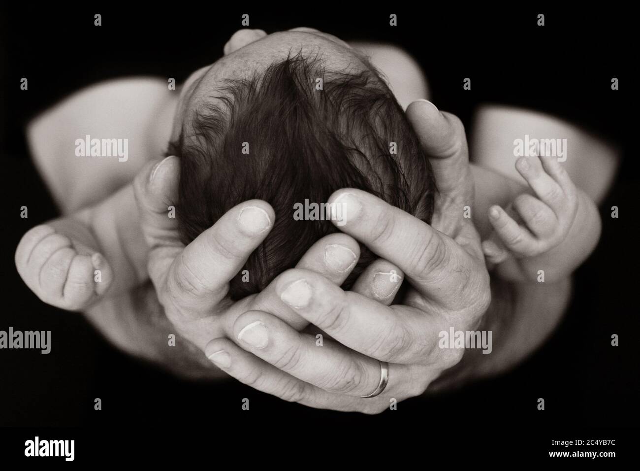 Padre che tiene la testa del bambino nelle mani Foto Stock