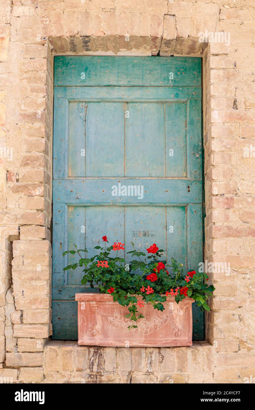 Una porta caratteristica con muratura sbriciolata bloccata da una piantatrice a Lucignano d’Asso, Toscana, Italia Foto Stock