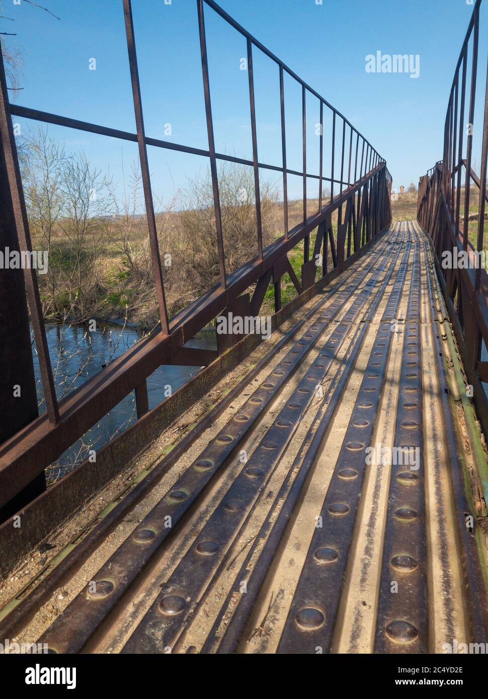 Ponte pedonale sospeso in metallo arrugginito sul piccolo fiume Sura in ucraina Foto Stock