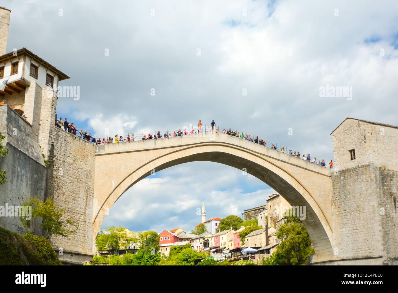 Un bosniaco locale si prepara a tuffarsi dallo Stari Most, il vecchio ponte nella città vecchia di Mostar, Bosnia ed Erzegovina, mentre i turisti si riuniscono per guardare il salto Foto Stock