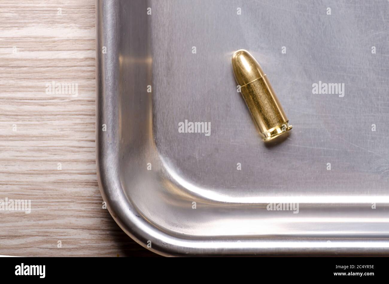 una singola cartuccia completamente in metallo rivestita è posizionata nell'angolo di un vassoio argento Foto Stock