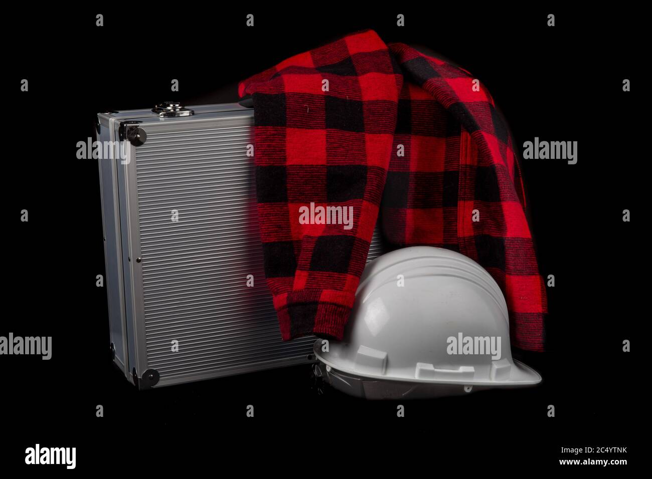 una camicia rossa e un elmetto bianco su una custodia in alluminio isolata in nero Foto Stock
