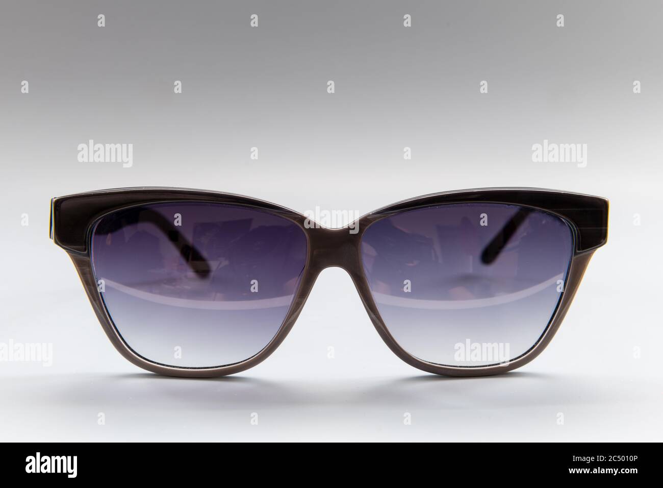 Un paio di occhiali da sole firmati isolati con uno sfondo grigio. Foto Stock