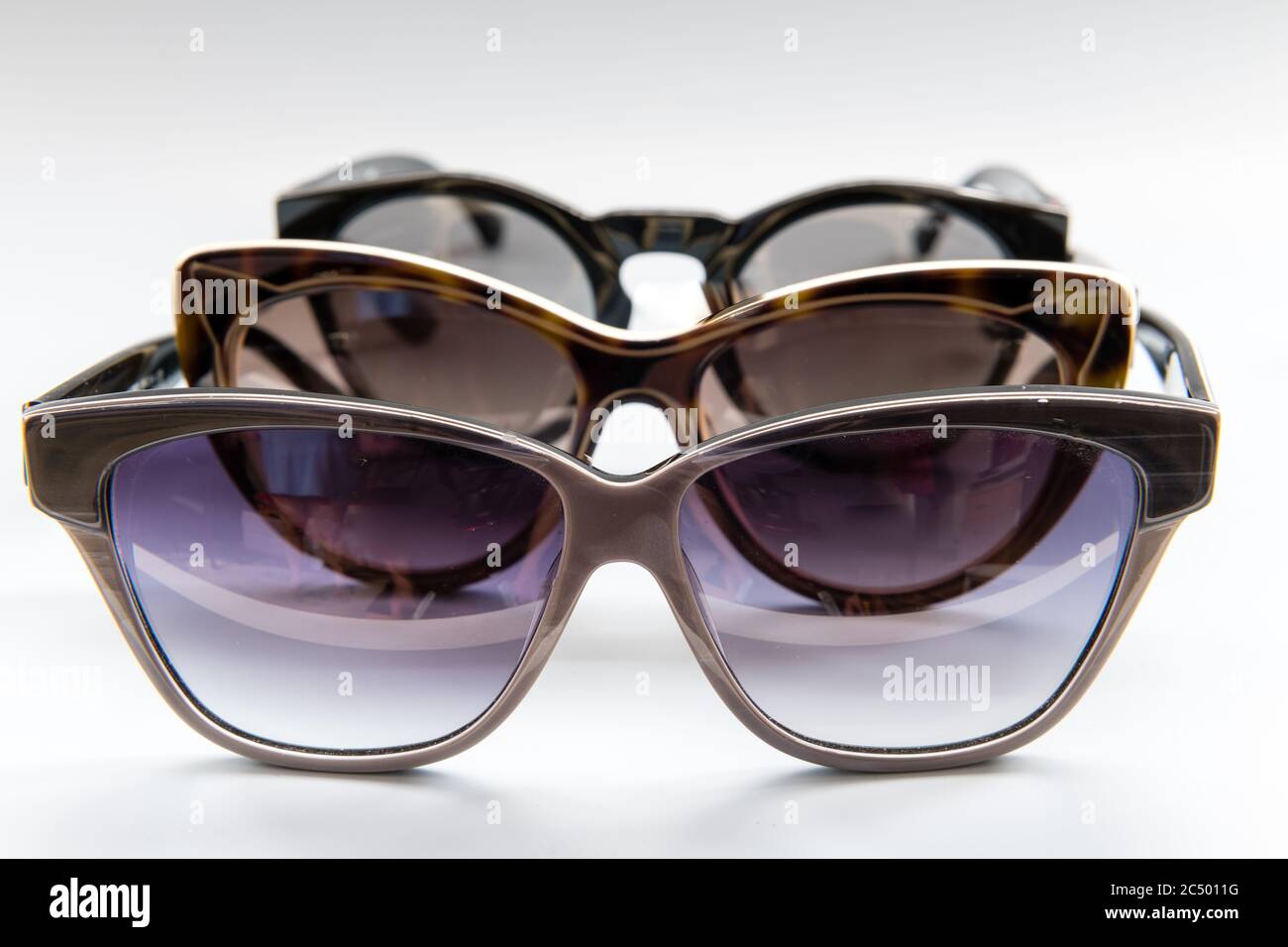 Una fila di occhiali da sole firmati isolati con uno sfondo grigio. Foto Stock