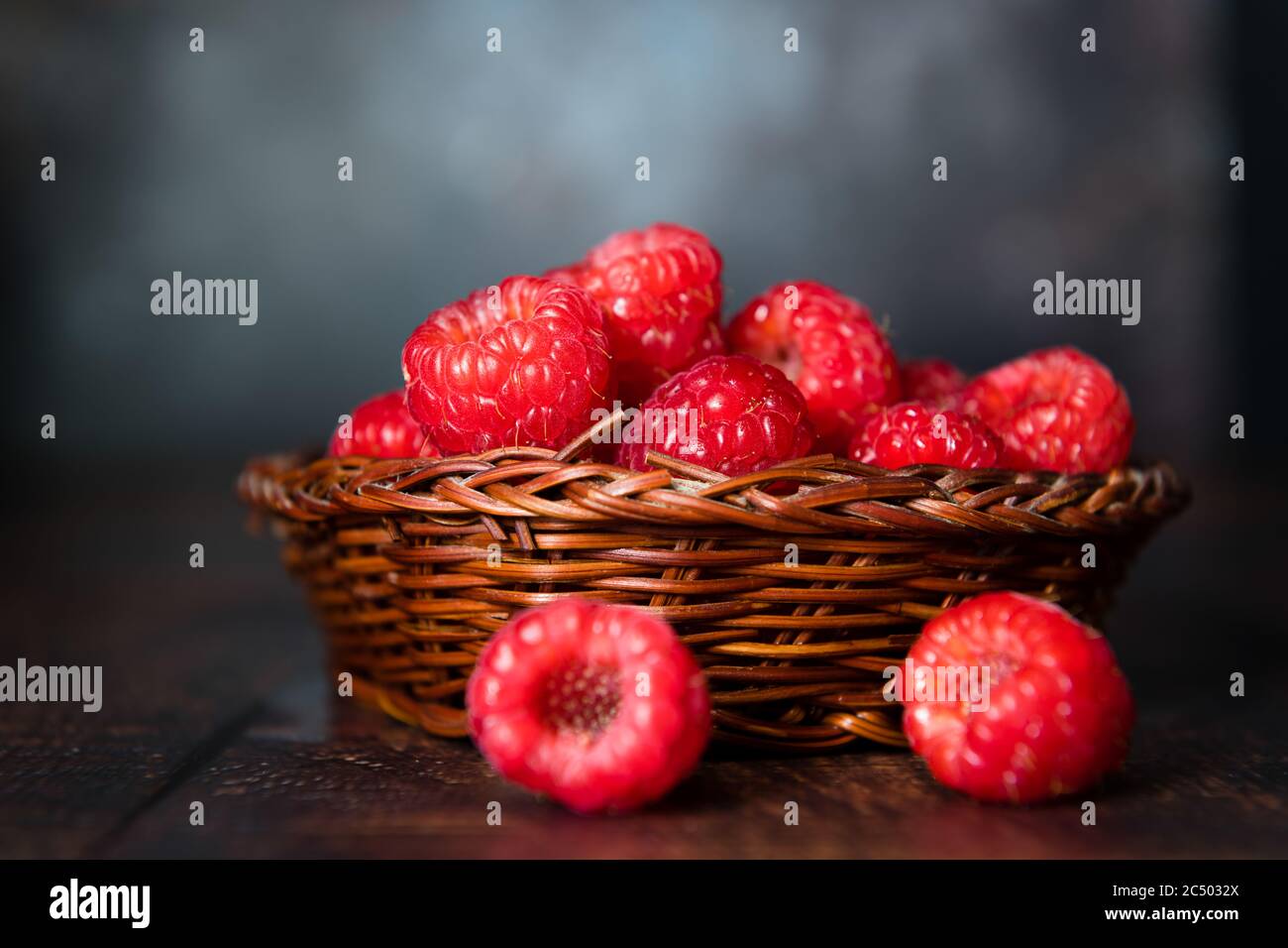 Un vimini pieno di raspi isolati con uno sfondo scuro. Foto Stock