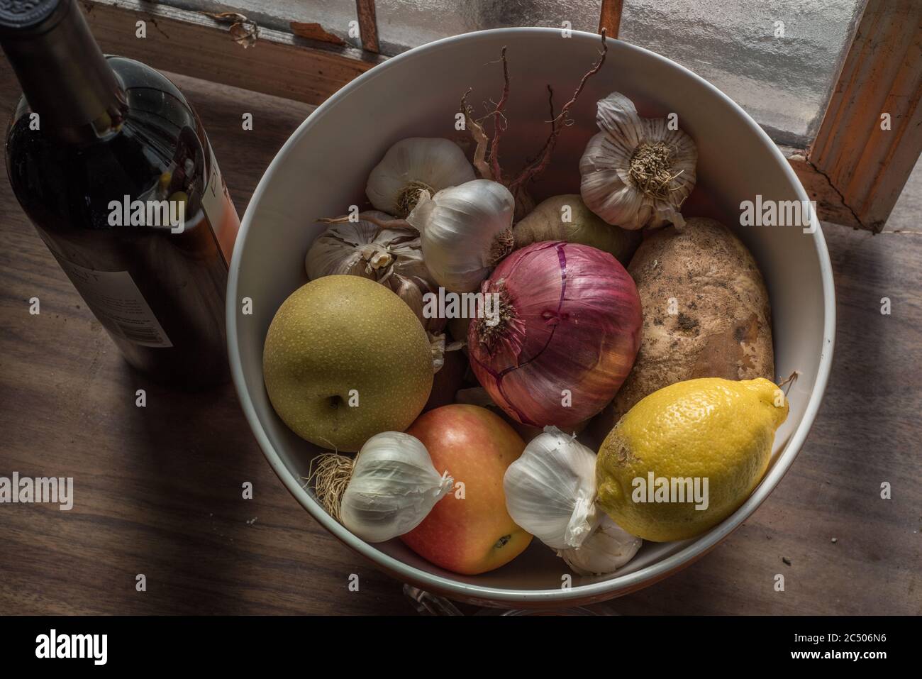Una vita morta di una ciotola di frutta e verdura mista seduta su un piano di un bancone in una cucina. Foto Stock