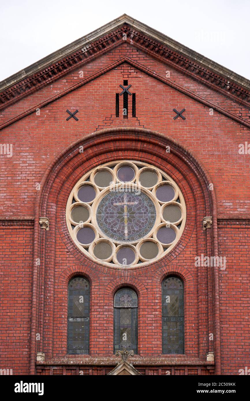 Grande finestra rotonda posta in mattoni rossi muro di una chiesa Foto Stock
