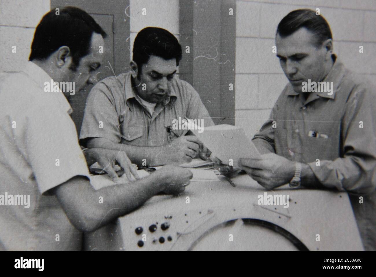Bella fotografia in bianco e nero degli anni '70 di tre professionisti che tengono una riunione di strategia. Foto Stock