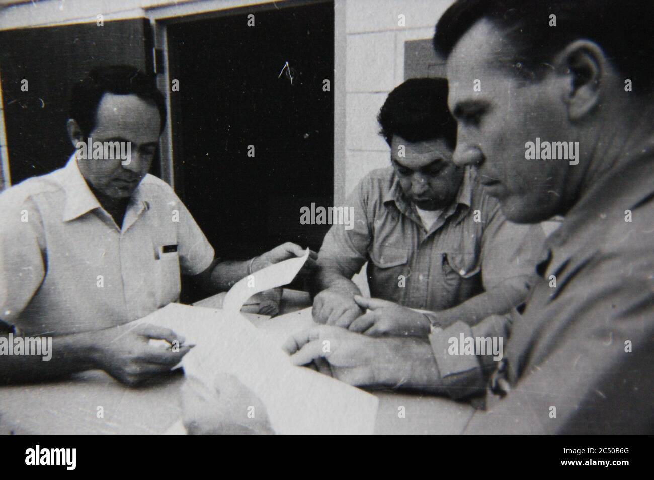 Bella fotografia in bianco e nero degli anni '70 di tre professionisti che tengono una riunione di strategia. Foto Stock