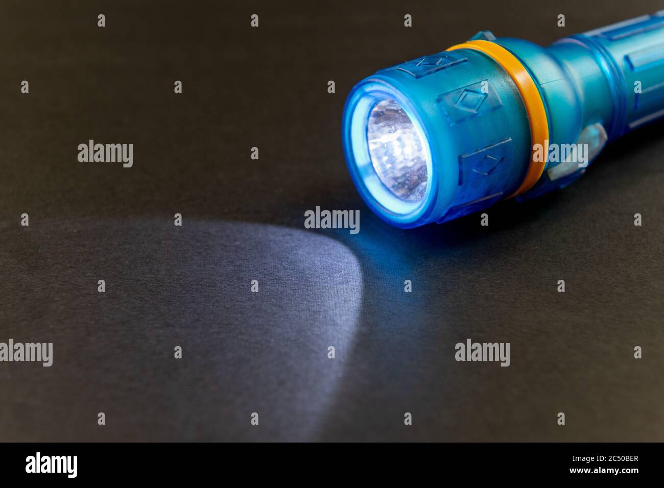 Una torcia a batteria che illumina la sua luce su una superficie nera. Foto Stock