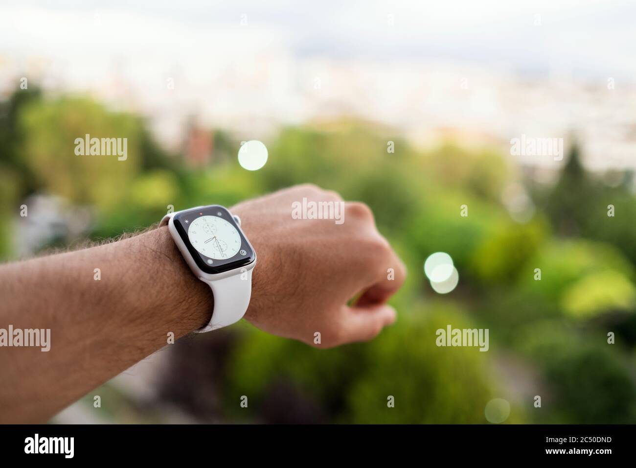 Izmir, Turchia - 11 giugno 2020: Primo piano dell'orologio Apple colorato bianco di quinta generazione con marchio Apple su un polso mans e sfondo verde sfocato. Foto Stock