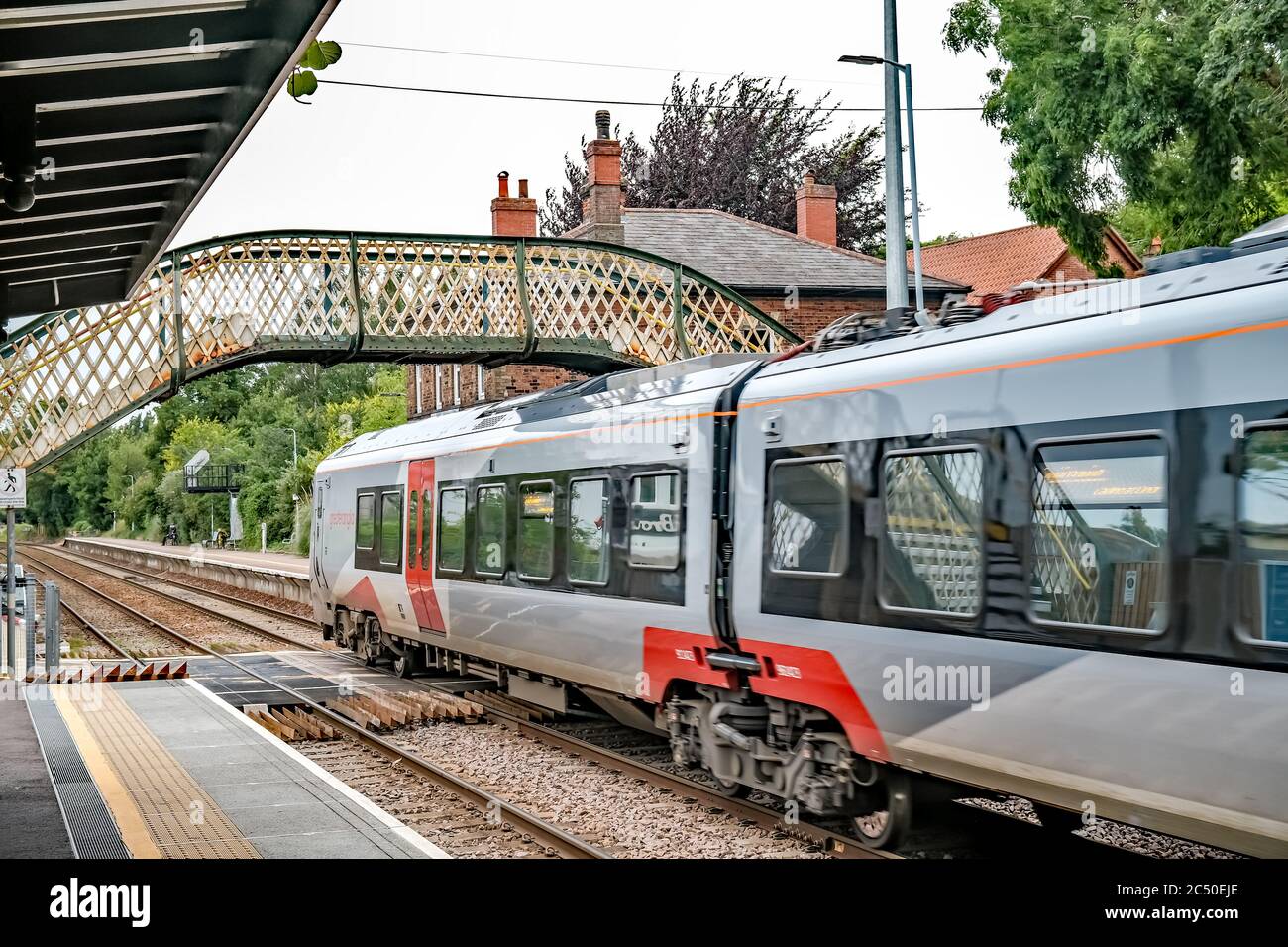 Treno Greater Anglia con partenza dalla stazione ferroviaria di Brundall Gardens, catturata dal ponte pedonale sopra la cima della ferrovia Foto Stock