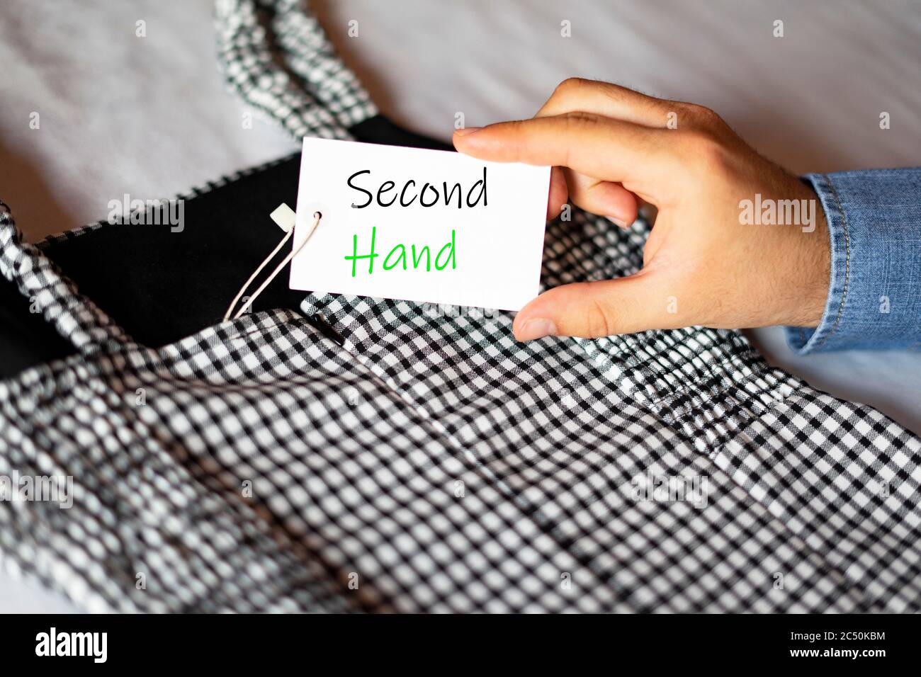 Uomo che prende un'etichetta che dice la seconda mano. Etichetta di abbigliamento. Abbigliamento usato. Foto Stock