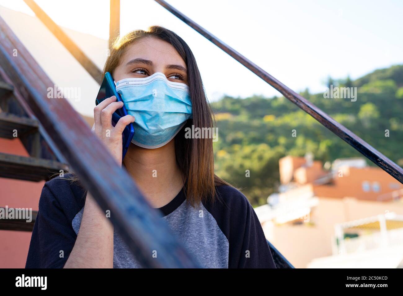 Donna con maschera che parla al telefono. Concetto di maschera e COVID-19. Maschera blu e telefono blu. Foto Stock