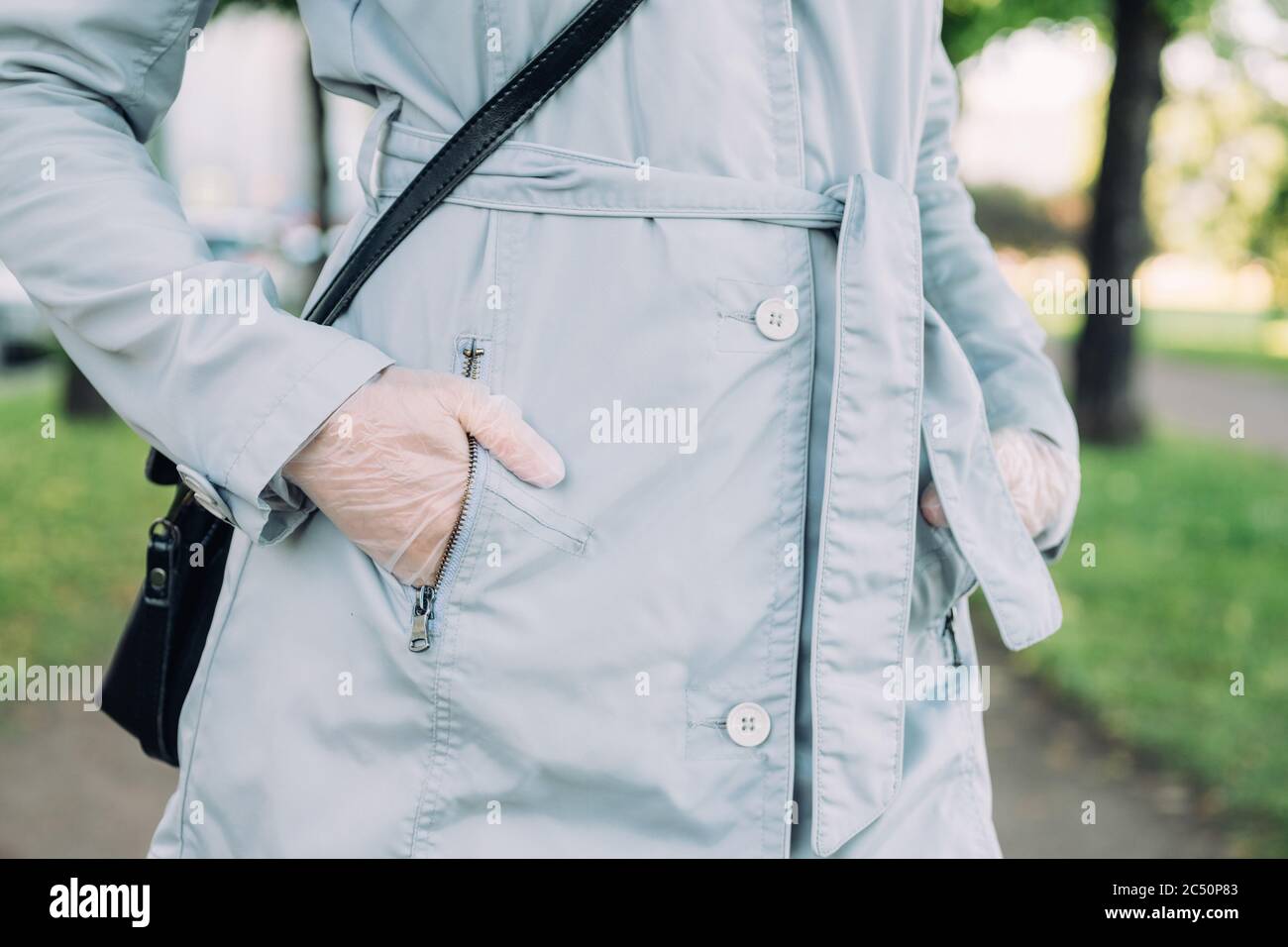 Ragazza in guanti medici mettere la sua mano nella tasca di un cappotto di primavera. Foto Stock