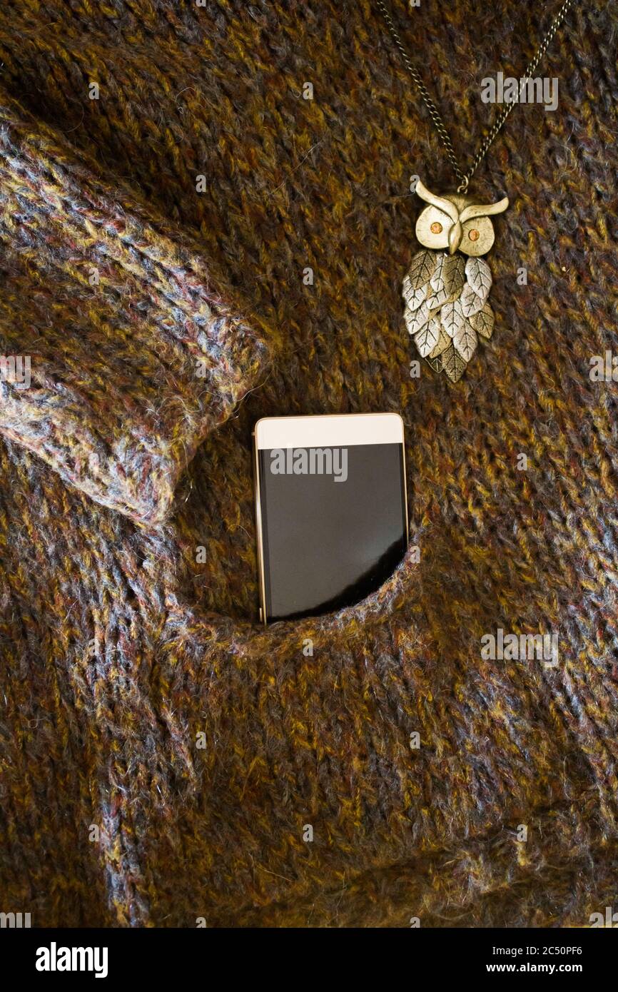 Maglia marrone di lana invernale in tasca con telefono Foto Stock