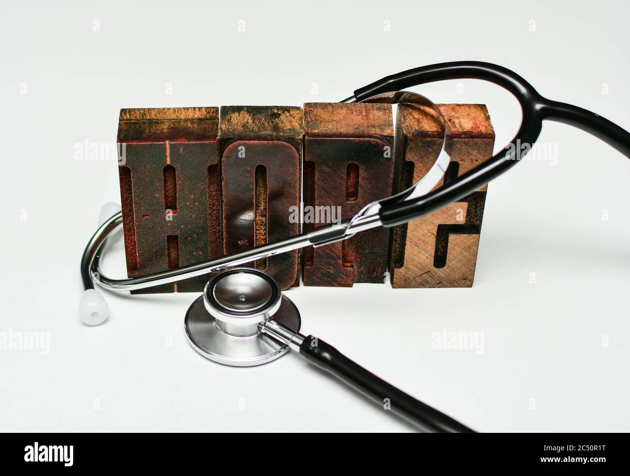 Stetoscopio anr la parola 'speranza' fatta di lettere tipografiche in legno. Assistenza sanitaria, aspettative di risultati positivi, speranza di ripresa, med di alta qualità Foto Stock