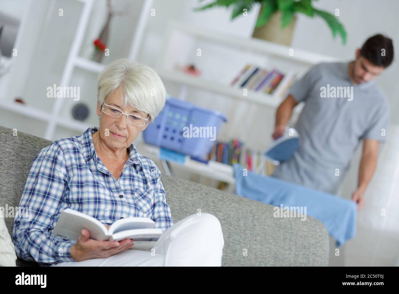 donna anziana sul divano con assistente Foto Stock