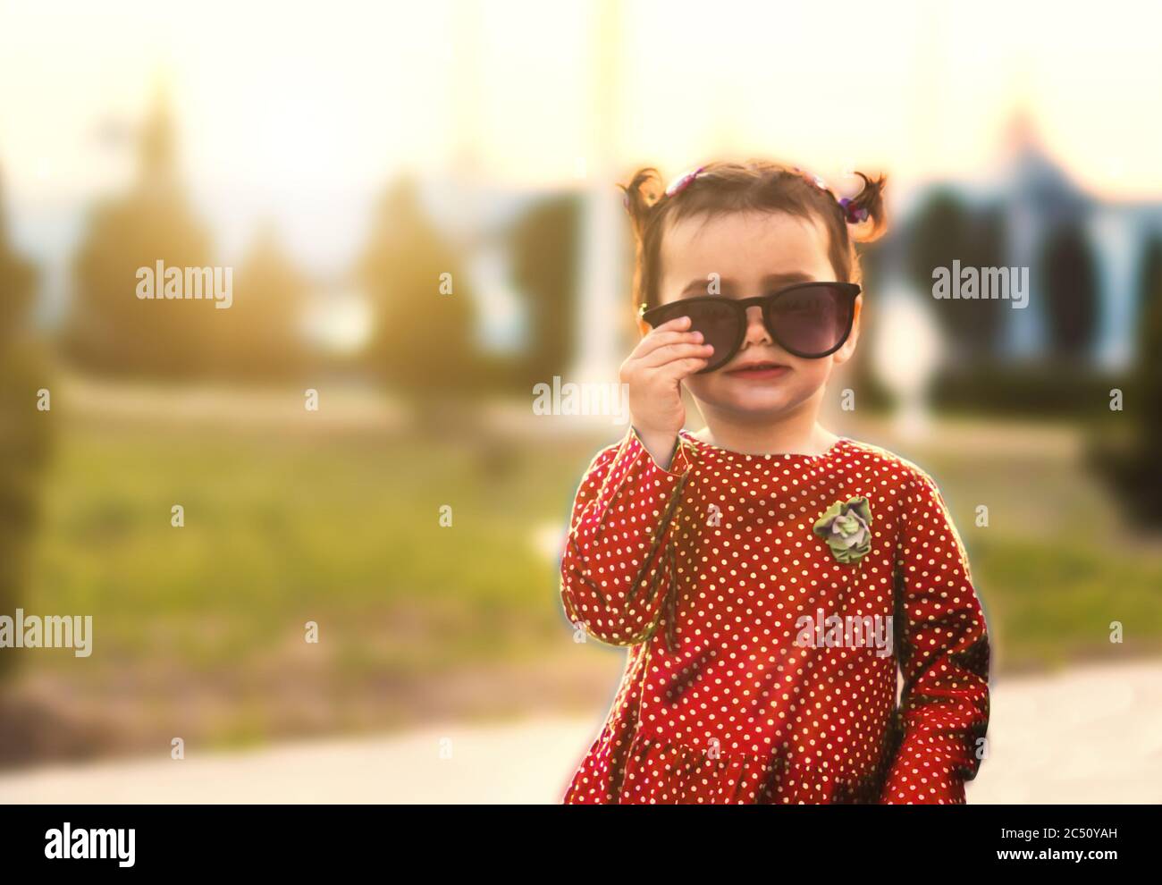 ragazza elegante in un vestito rosso e occhiali da sole Foto Stock