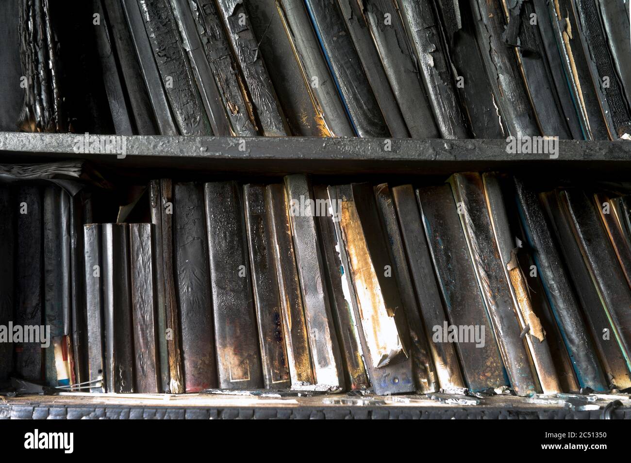 Libreria con spine del libro danneggiate dopo il fuoco, primo piano interno Foto Stock