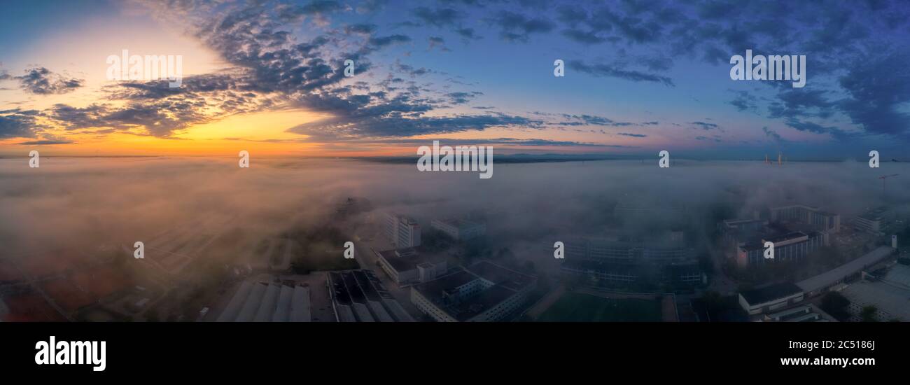 Vista dell'alba al mattino in nebbia su un quartiere degli affari con edifici di uffici coperti dalla nebbia imminente della mattina presto. Foto Stock