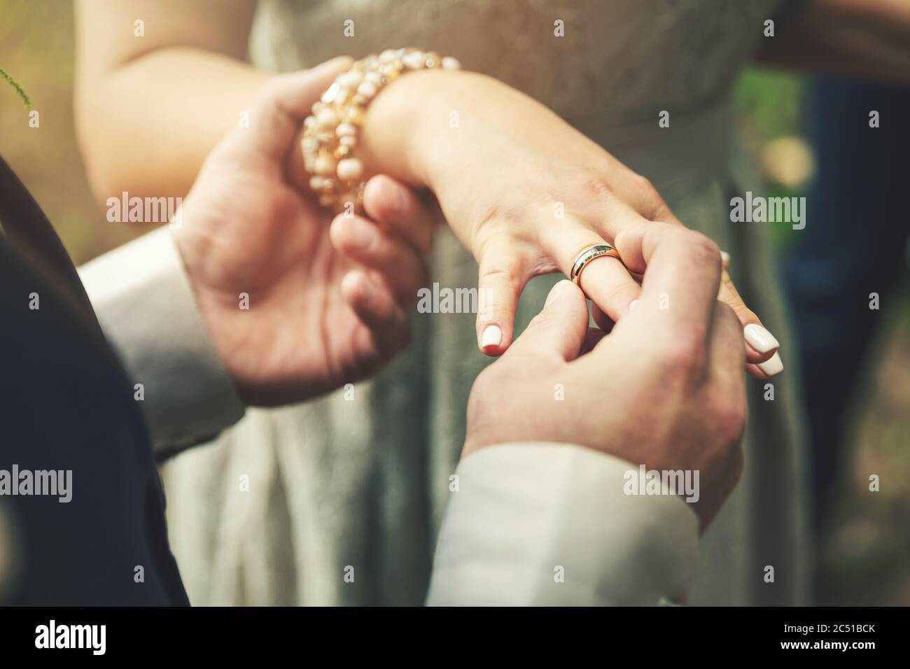 sposo mettendo l'anello di nozze sulla mano della sposa Foto Stock