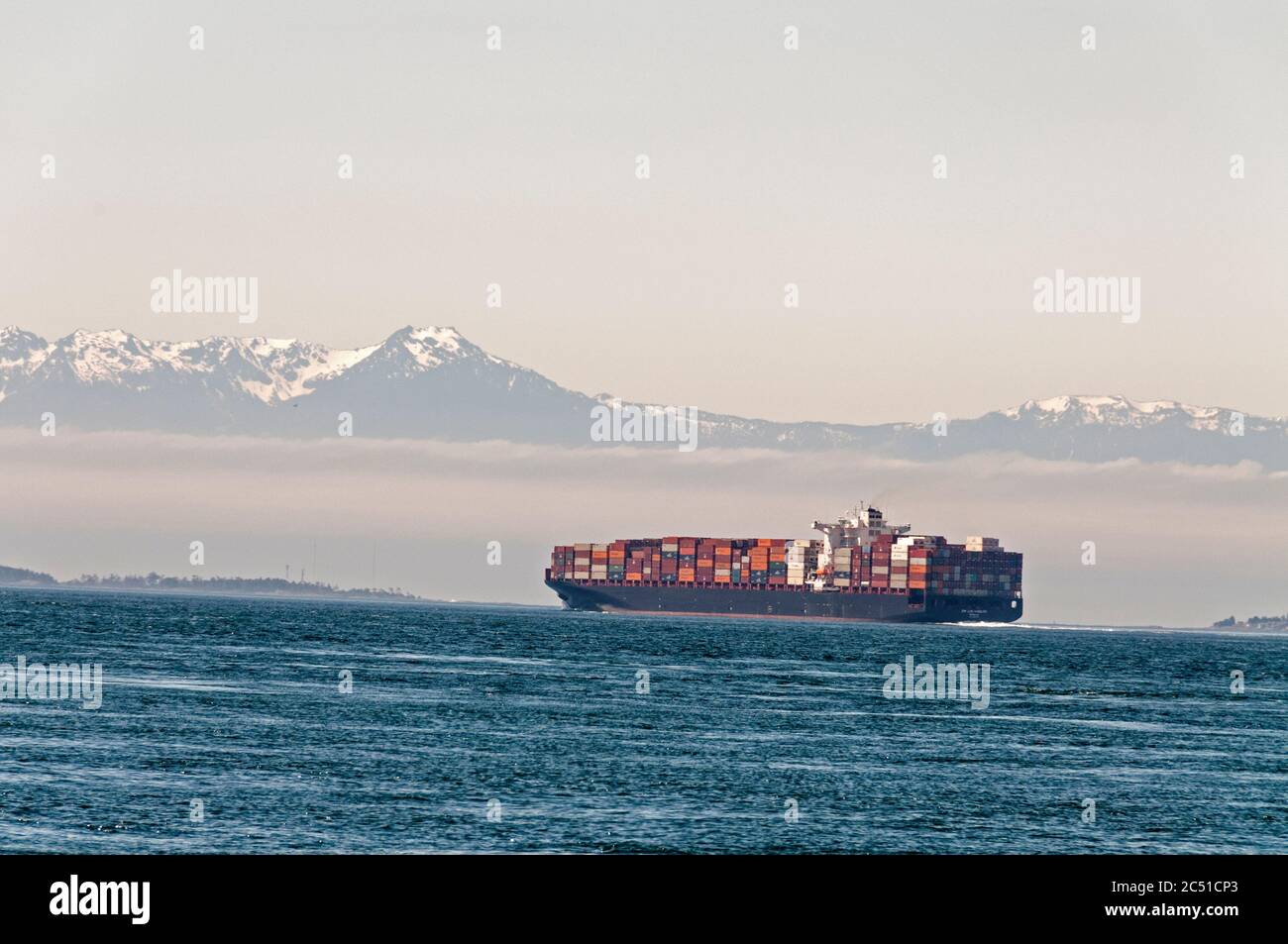 Una nave di container di carico che naviga all'ombra delle montagne olimpiche negli Stati Uniti vicino a Vancouver Island, Canada. Foto Stock